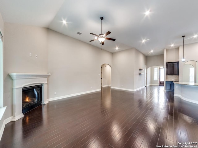 unfurnished living room with dark hardwood / wood-style flooring, vaulted ceiling, and ceiling fan