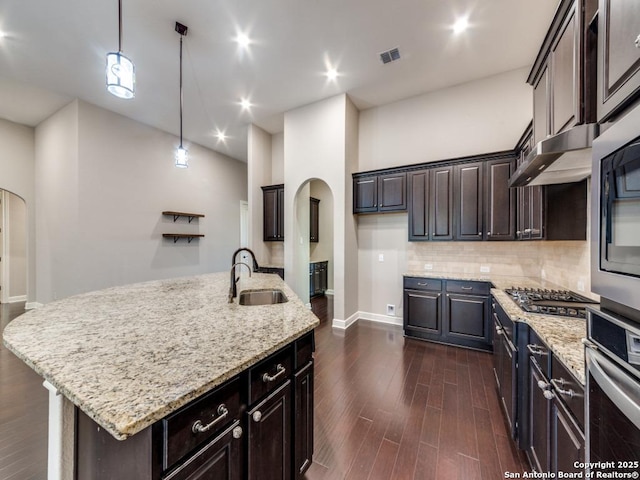 kitchen featuring sink, appliances with stainless steel finishes, dark hardwood / wood-style floors, an island with sink, and decorative light fixtures