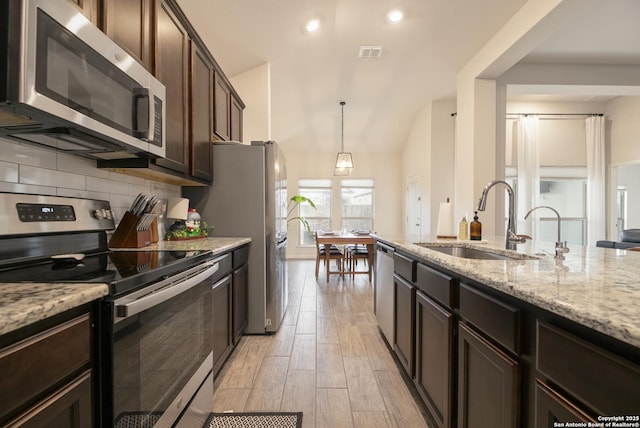 kitchen with sink, decorative light fixtures, dark brown cabinets, appliances with stainless steel finishes, and backsplash