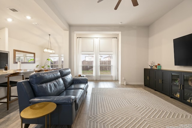 living room featuring ceiling fan, a healthy amount of sunlight, and vaulted ceiling