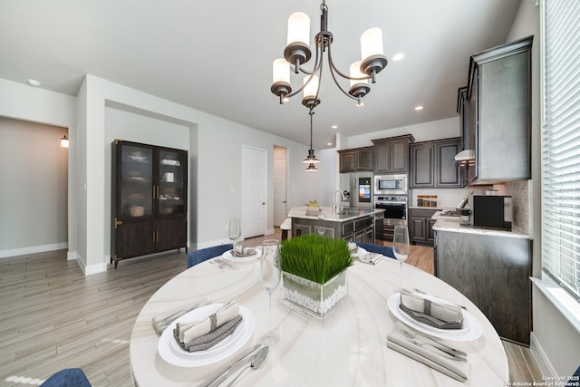 dining room featuring a wealth of natural light, sink, an inviting chandelier, and light wood-type flooring