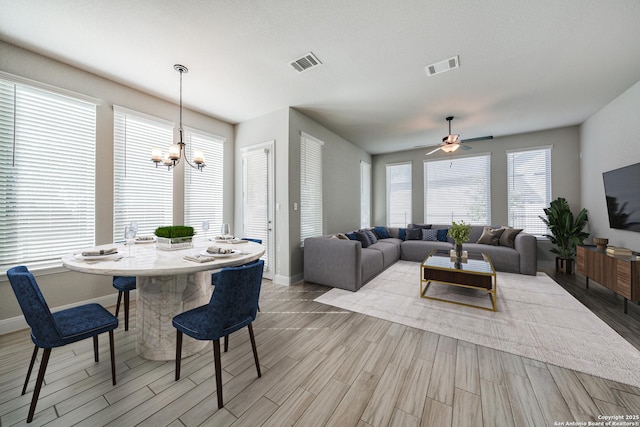 dining space with ceiling fan with notable chandelier and light hardwood / wood-style floors