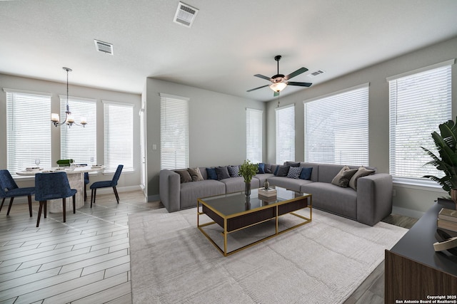 living room featuring ceiling fan with notable chandelier and light hardwood / wood-style flooring