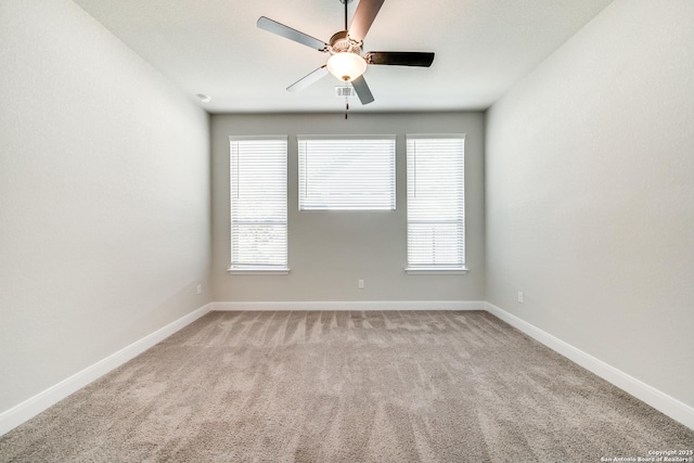 carpeted spare room featuring ceiling fan and a wealth of natural light