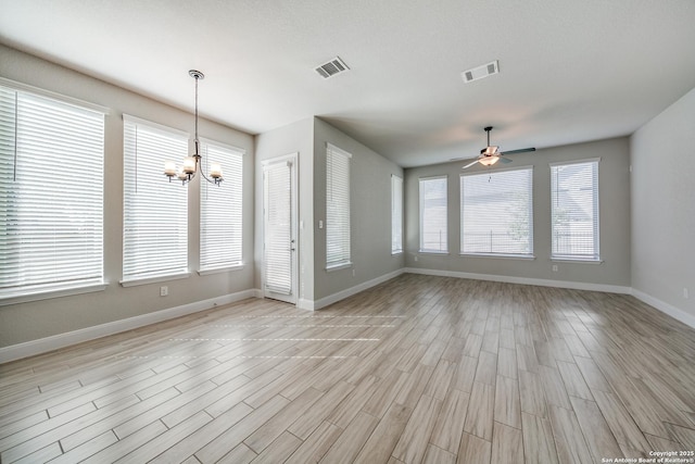 unfurnished living room with ceiling fan with notable chandelier and light hardwood / wood-style flooring