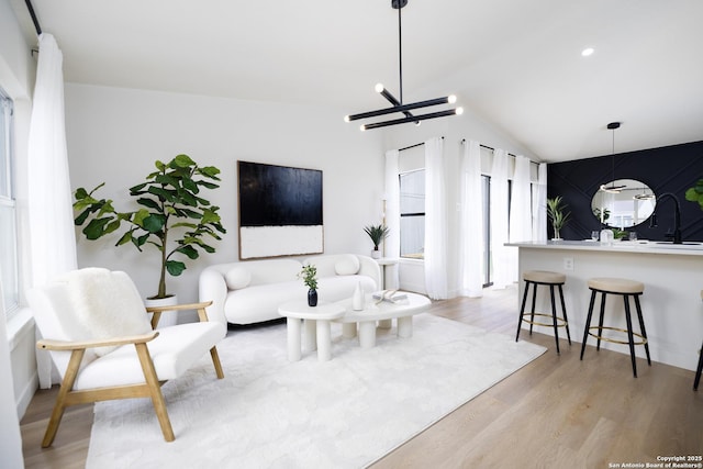 living room featuring lofted ceiling, a notable chandelier, and light hardwood / wood-style floors