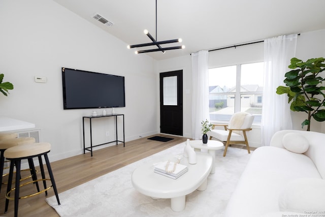 living room featuring an inviting chandelier, lofted ceiling, and light wood-type flooring