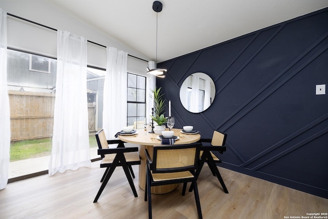 dining room featuring wood-type flooring and vaulted ceiling