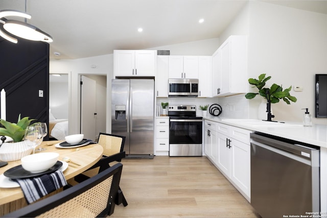 kitchen with sink, white cabinetry, light wood-type flooring, appliances with stainless steel finishes, and backsplash