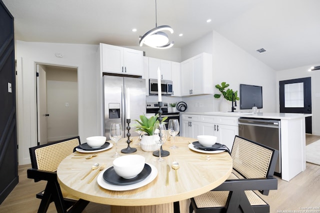 dining space with lofted ceiling and light hardwood / wood-style flooring