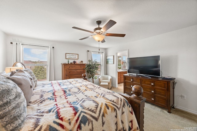 bedroom with light colored carpet, ceiling fan, and ensuite bathroom