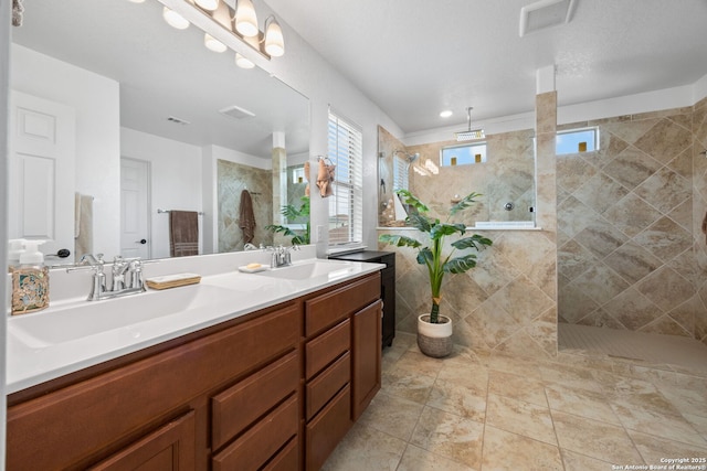 bathroom with tiled shower and vanity