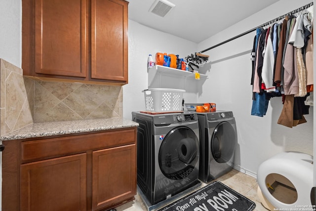 laundry area with light tile patterned floors, washer and clothes dryer, and cabinets