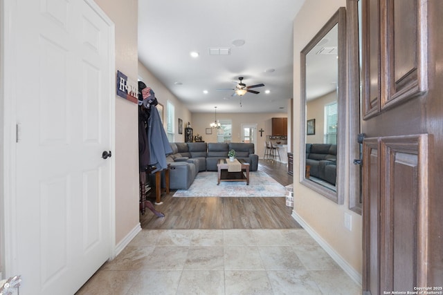 tiled living room with ceiling fan with notable chandelier