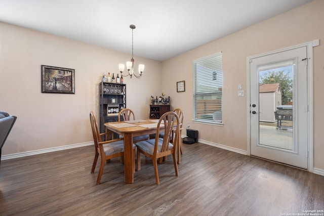 dining space featuring dark wood-type flooring and an inviting chandelier