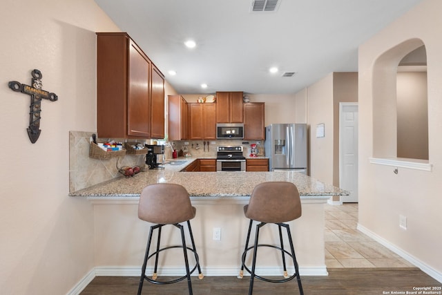 kitchen featuring appliances with stainless steel finishes, a kitchen breakfast bar, and kitchen peninsula