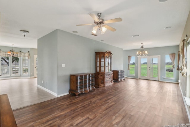 unfurnished living room with wood-type flooring, a healthy amount of sunlight, and ceiling fan with notable chandelier