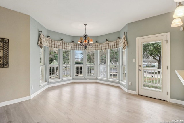 unfurnished dining area with an inviting chandelier and light wood-type flooring