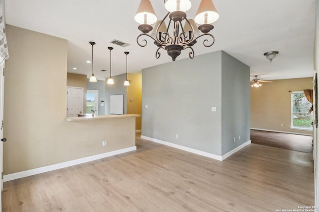 spare room with ceiling fan with notable chandelier and light hardwood / wood-style floors