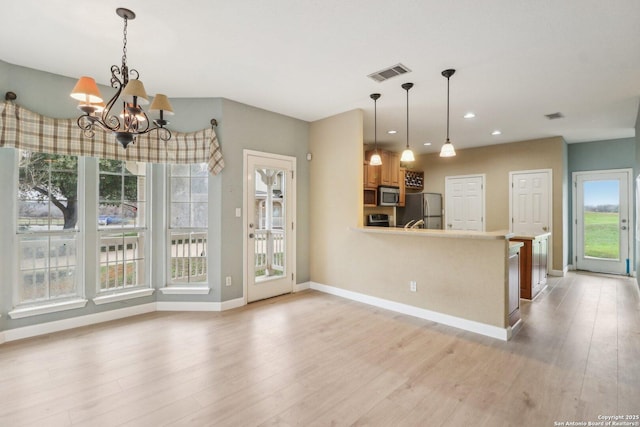 kitchen with a notable chandelier, decorative light fixtures, stainless steel appliances, and light hardwood / wood-style floors