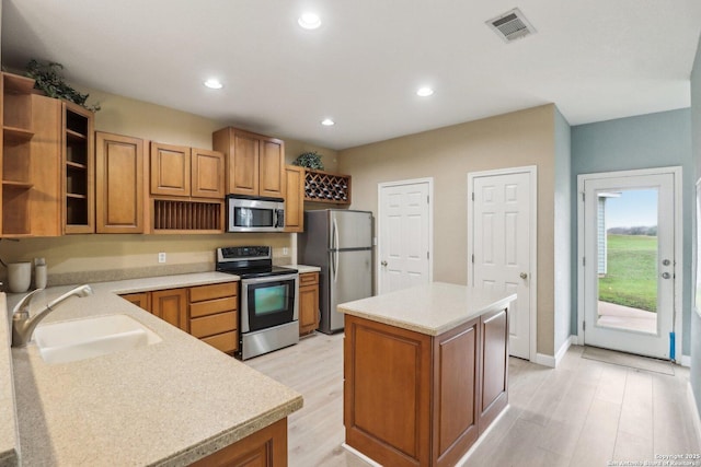 kitchen featuring sink, stainless steel appliances, a center island, and light wood-type flooring