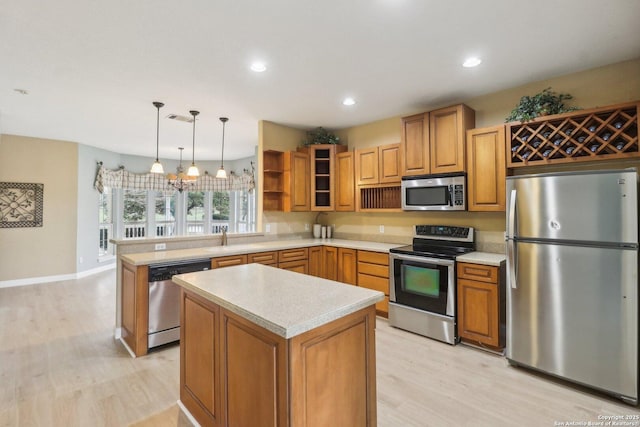 kitchen with hanging light fixtures, stainless steel appliances, light hardwood / wood-style floors, a kitchen island, and kitchen peninsula