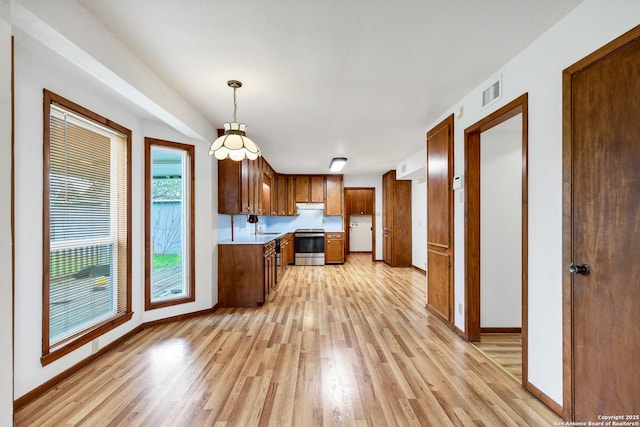 kitchen featuring pendant lighting, sink, stainless steel range, and light hardwood / wood-style floors