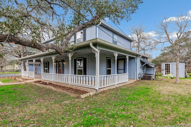 view of front facade with a porch, a front yard, and a storage shed