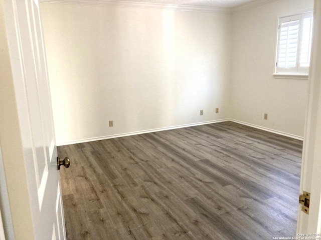 spare room featuring dark wood-type flooring and ornamental molding