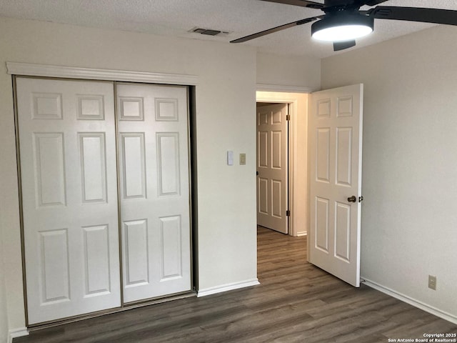 unfurnished bedroom with ceiling fan, a textured ceiling, dark hardwood / wood-style flooring, and a closet