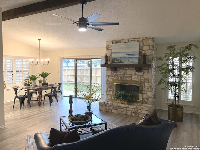 living room with hardwood / wood-style flooring, vaulted ceiling with beams, a textured ceiling, and a fireplace