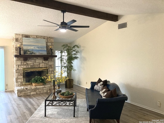 living room with ceiling fan, vaulted ceiling with beams, wood-type flooring, a fireplace, and a textured ceiling