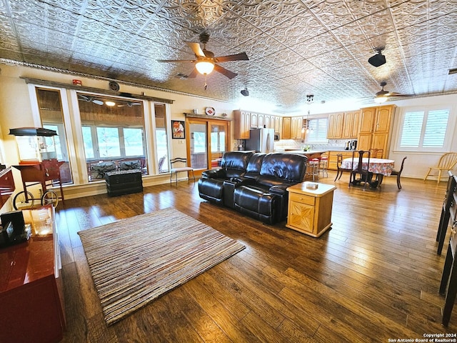 living area with ceiling fan, dark wood-style flooring, and an ornate ceiling