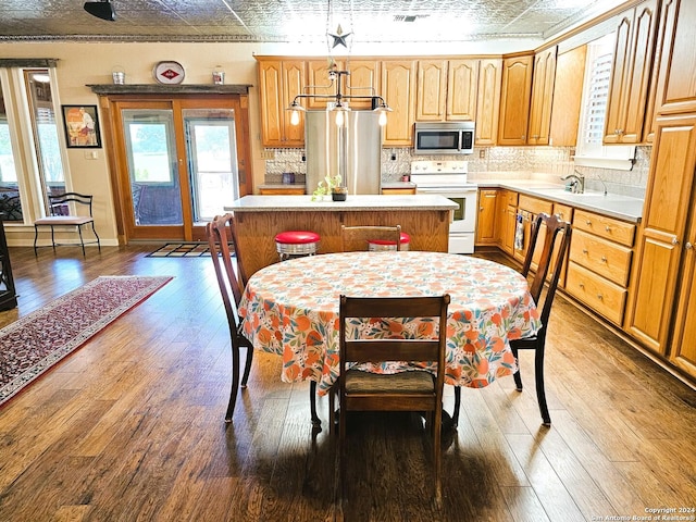 kitchen featuring stainless steel appliances, light countertops, a center island, an ornate ceiling, and pendant lighting