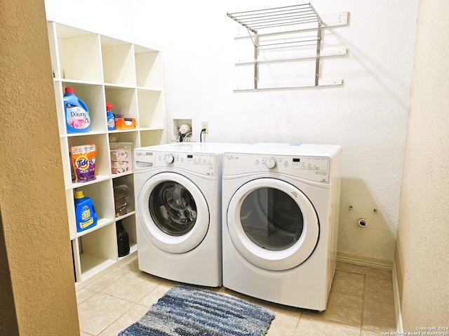 laundry area with a textured wall, light tile patterned flooring, laundry area, baseboards, and washing machine and clothes dryer