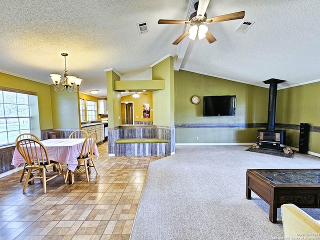 living area featuring ornamental molding, lofted ceiling, a wood stove, and visible vents