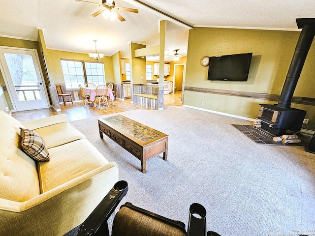 living area featuring lofted ceiling, ornamental molding, a wood stove, light carpet, and ceiling fan with notable chandelier