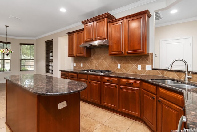 kitchen featuring sink, crown molding, stainless steel gas cooktop, a kitchen island, and decorative light fixtures