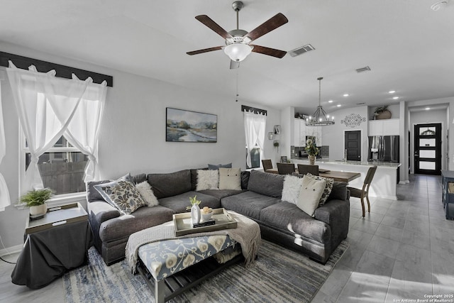 living room with ceiling fan with notable chandelier