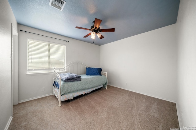 carpeted bedroom featuring ceiling fan and a textured ceiling