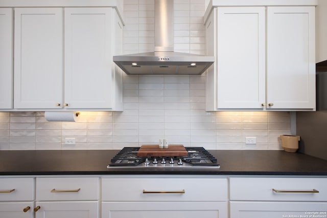 kitchen featuring tasteful backsplash, white cabinets, stainless steel gas cooktop, and wall chimney range hood