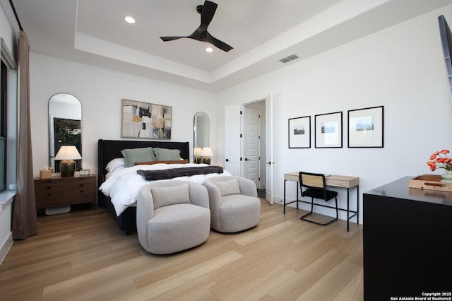 bedroom featuring a raised ceiling, ceiling fan, and light wood-type flooring