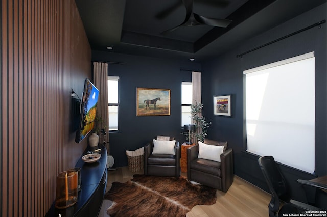 office space with ceiling fan, a wealth of natural light, a raised ceiling, and wood-type flooring