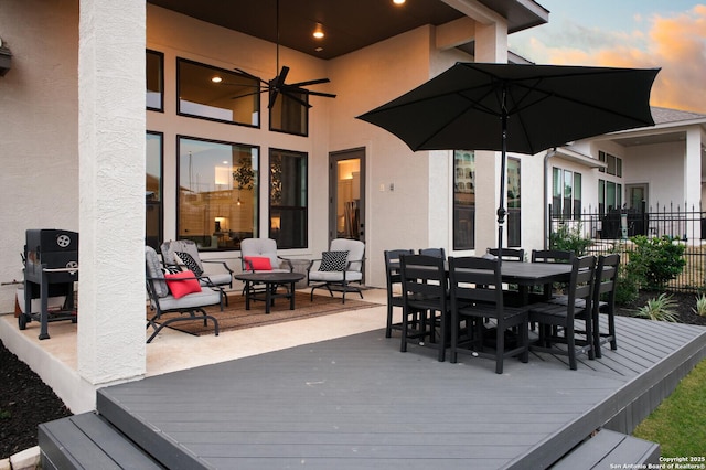 deck at dusk featuring ceiling fan and outdoor lounge area