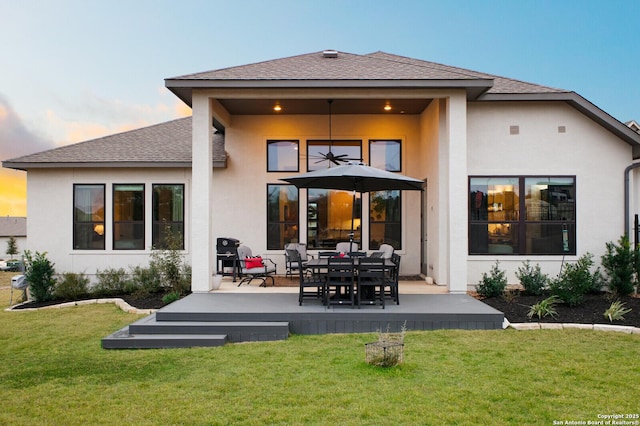 back house at dusk with a patio and a yard