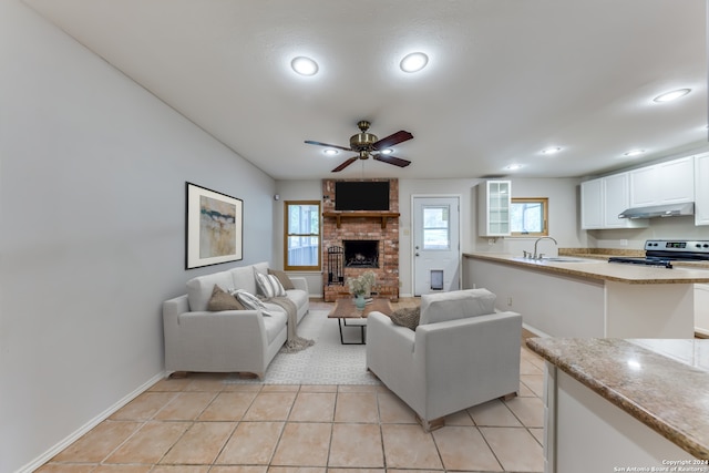 tiled living room with ceiling fan, sink, and a fireplace