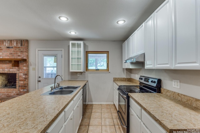 kitchen featuring sink, white cabinetry, a brick fireplace, appliances with stainless steel finishes, and a healthy amount of sunlight