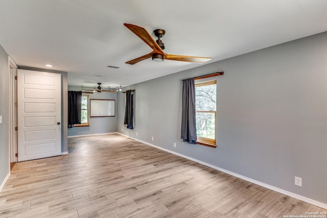 empty room featuring plenty of natural light, ceiling fan, and light wood-type flooring