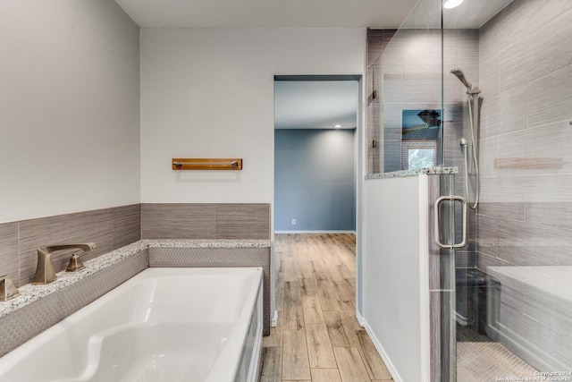 bathroom with wood-type flooring, independent shower and bath, and sink