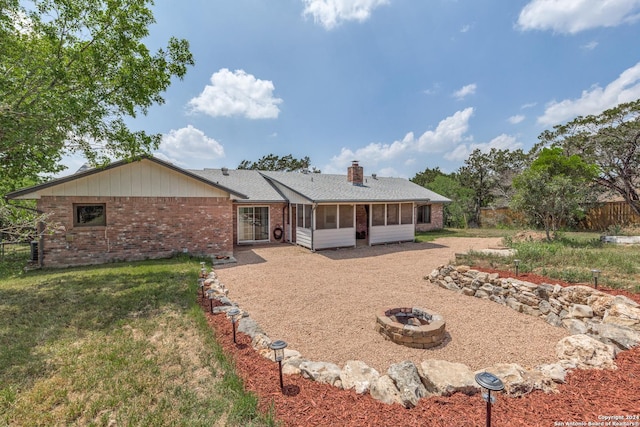 view of front of property with a front lawn, a fire pit, and a sunroom